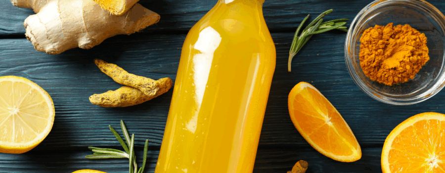 Orange juice in a glass bottle surrounded by nutrient dense food to target immune health