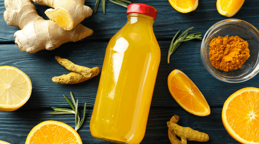 Orange juice in a glass bottle surrounded by nutrient dense food to target immune health